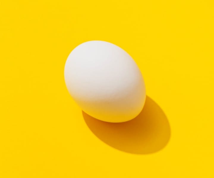 A white egg in a yellow background